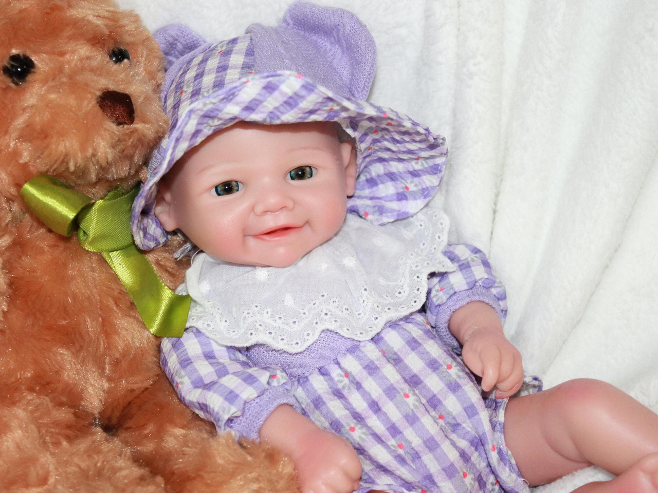 A baby doll dressed in a purple and white dress, featuring a sweet expression and soft, lifelike features.