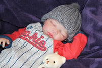 Thumbnail for A baby in a baseball uniform lies on a soft purple blanket, smiling and enjoying a playful moment.