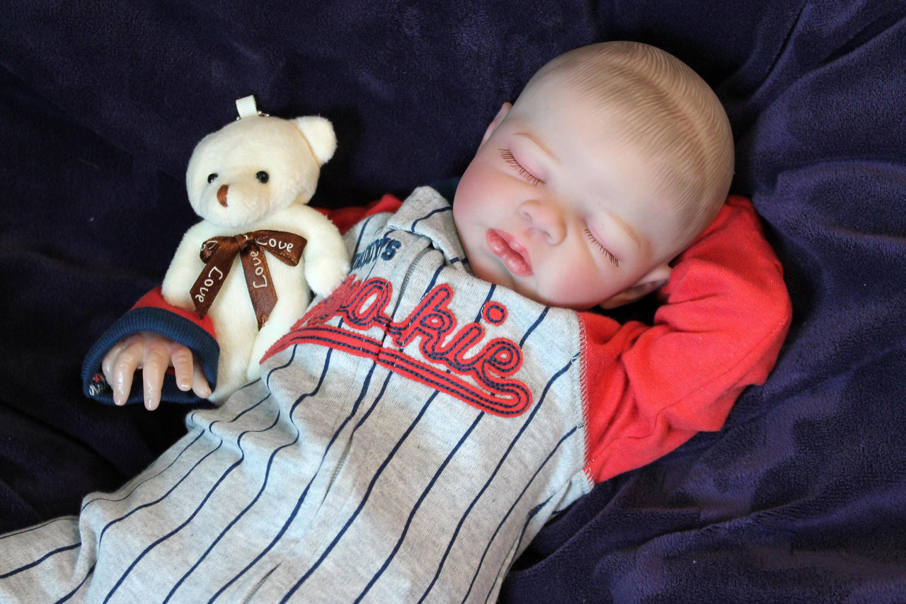 A baby wearing a baseball outfit rests on a cozy purple blanket, showcasing a delightful and playful appearance.