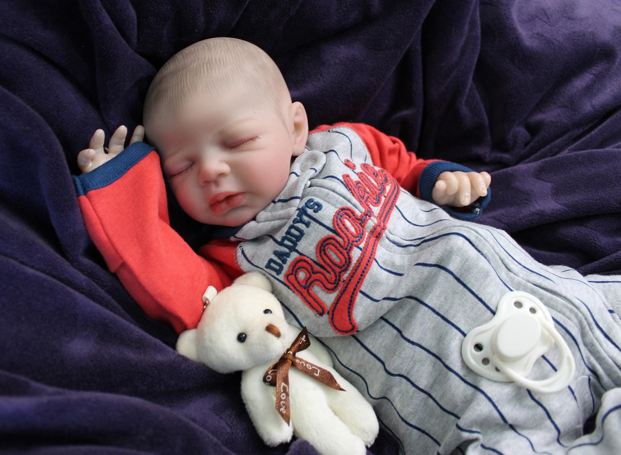 A baby wearing a baseball outfit rests on a cozy purple blanket, showcasing a delightful and playful appearance.