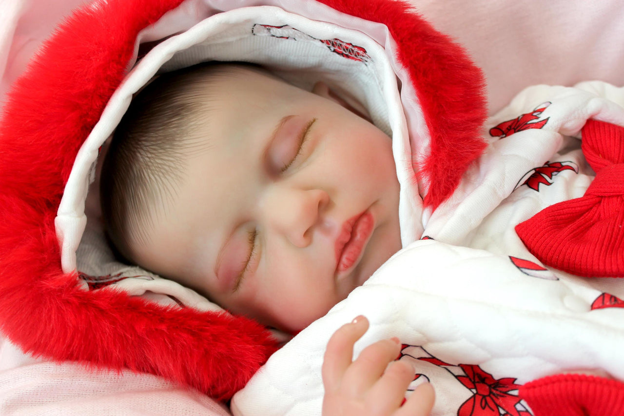 reborn doll in a red and white candy cane outfit with a furry red hood