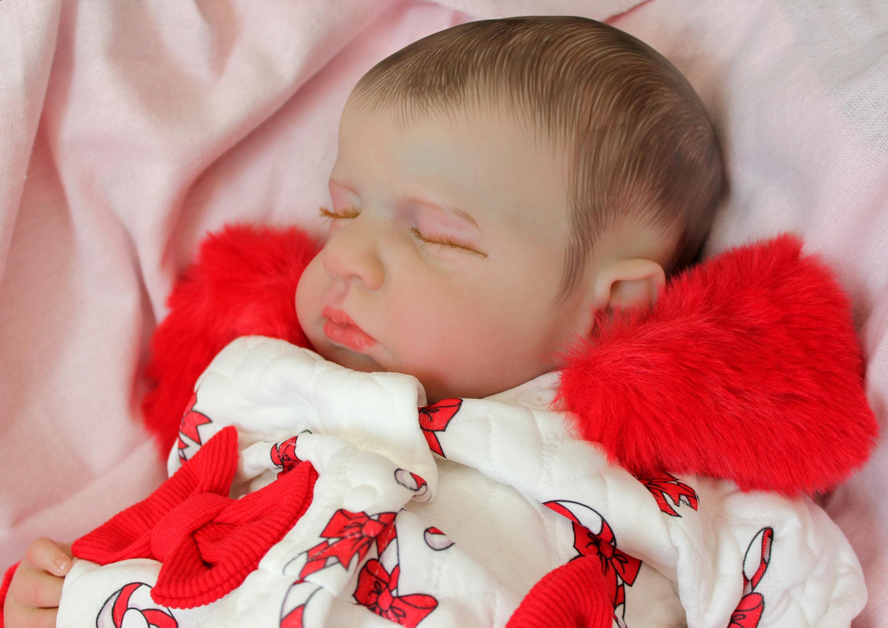 reborn doll in a red and white candy cane outfit with a furry red hood