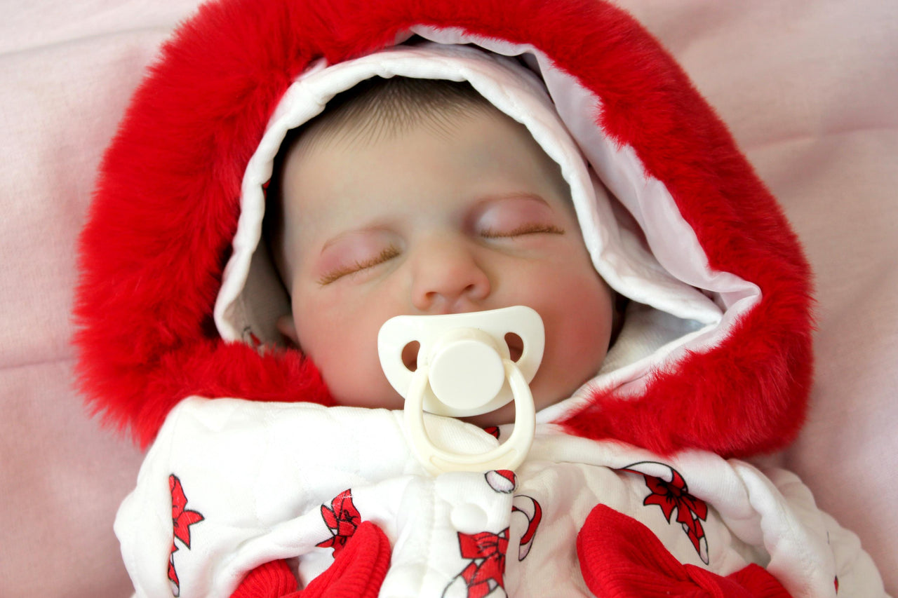 reborn doll in a red and white candy cane outfit with a furry red hood