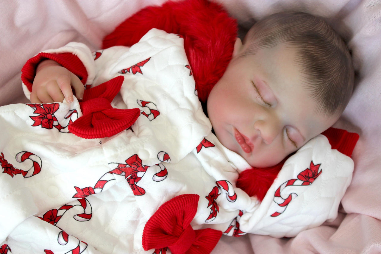 reborn doll in a red and white candy cane outfit with a furry red hood