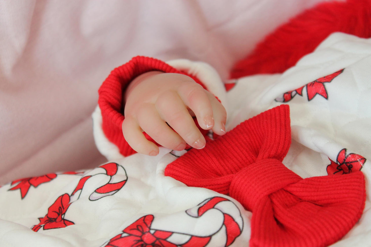 reborn doll in a red and white candy cane outfit with a furry red hood