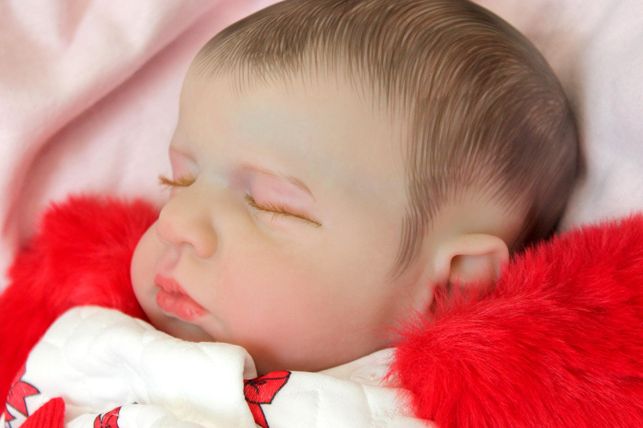 reborn doll in a red and white candy cane outfit with a furry red hood