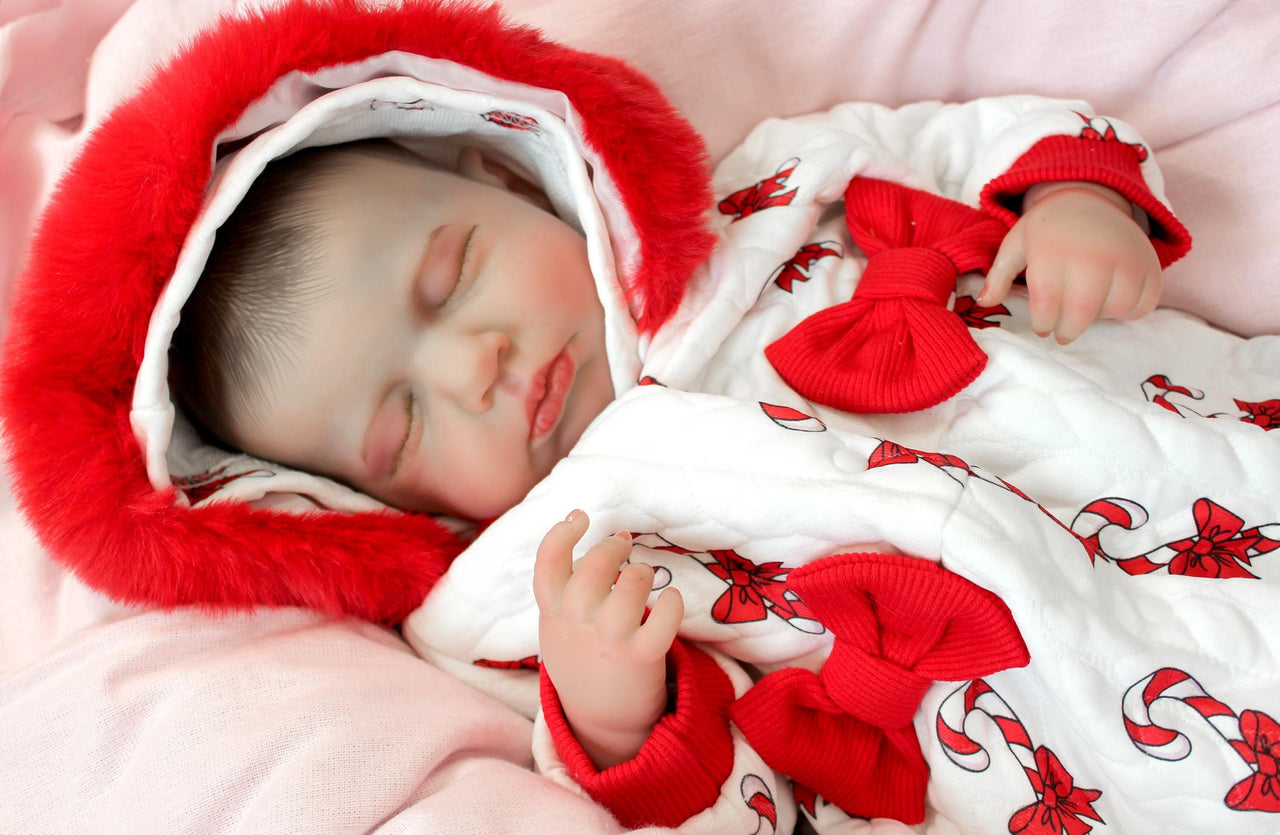 reborn doll in a red and white candy cane outfit with a furry red hood