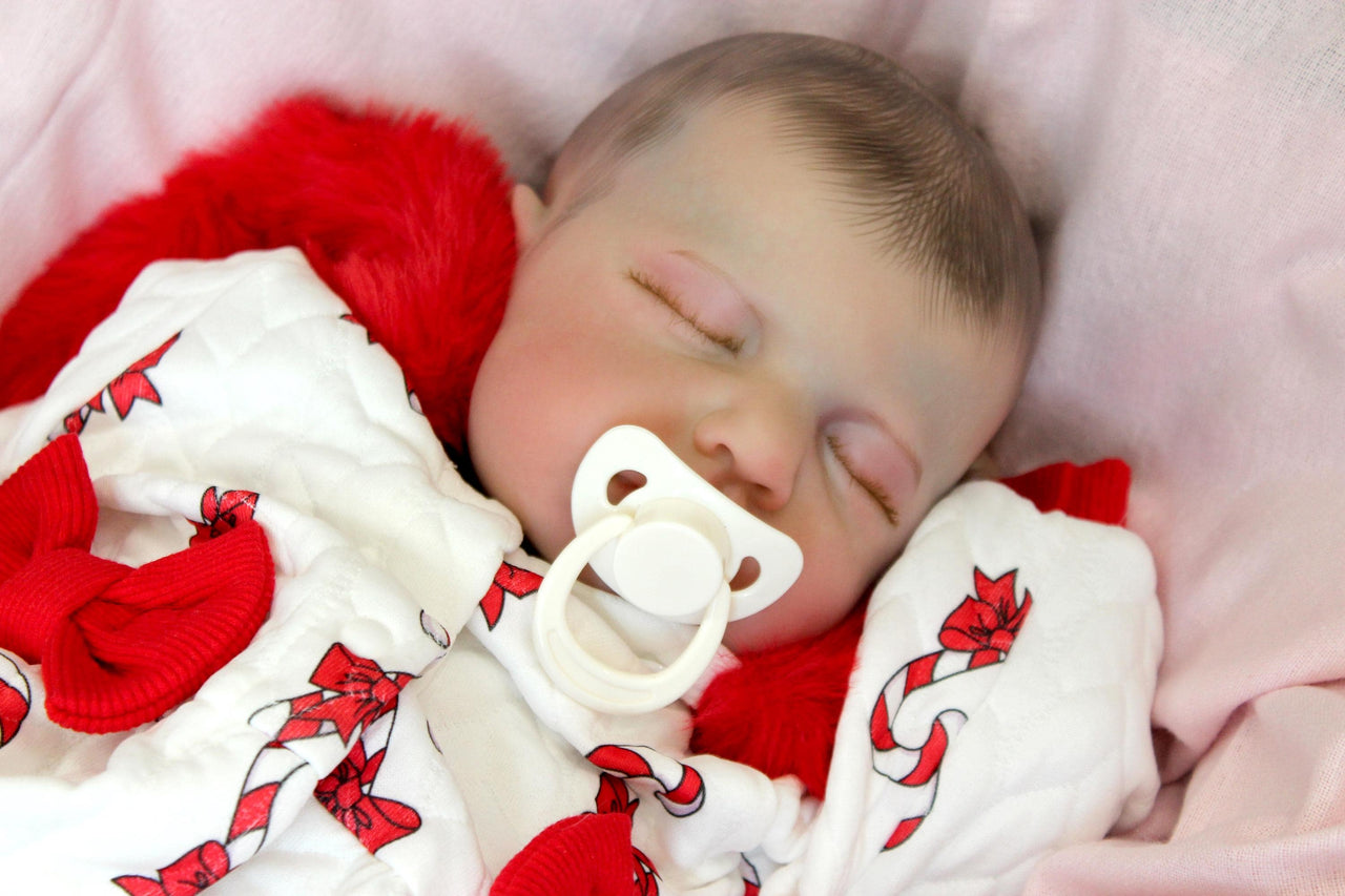 reborn doll in a red and white candy cane outfit with a furry red hood