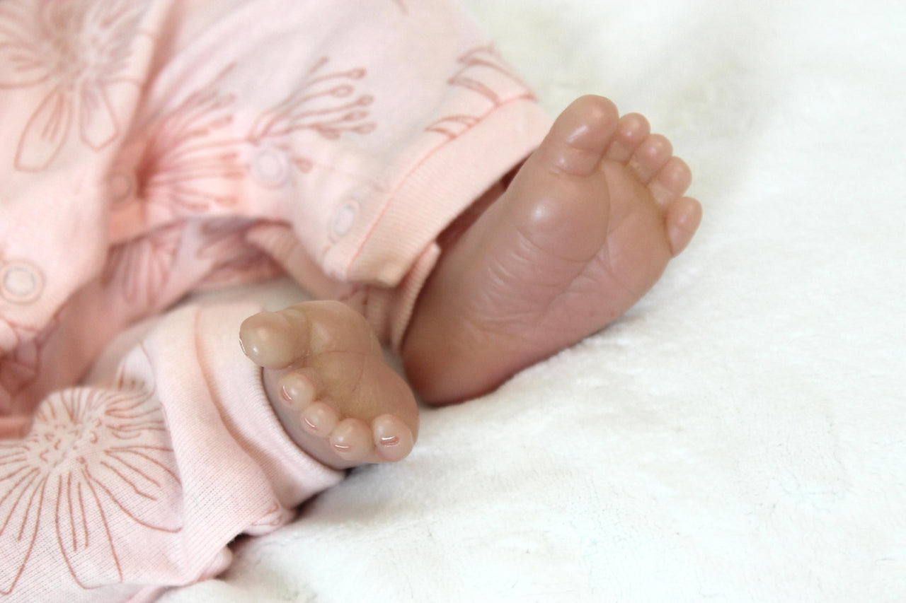 A baby doll peacefully sleeps, dressed in a soft pink outfit, exuding a sense of calm and innocence.