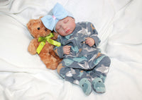 Thumbnail for A baby adorned with a bow, gently holding a teddy bear, radiating innocence and joy.