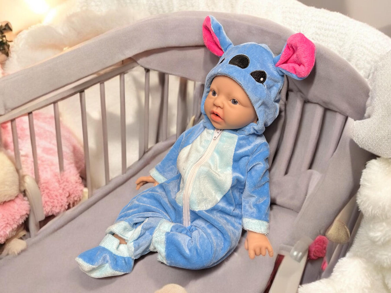 A baby doll wearing a blue outfit, featuring a cute expression and soft, plush material.