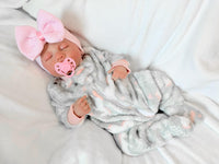 Thumbnail for Newborn baby girl in a gray outfit with a pink bow, peacefully resting on a soft blanket.