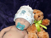 Thumbnail for A baby doll rests on a soft purple blanket beside a cuddly teddy bear, creating a serene and playful scene.