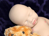 Thumbnail for Full Silicone Doll baby doll rests on a soft purple blanket beside a cuddly teddy bear, creating a serene and playful scene.