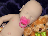 Thumbnail for Full Silicone Doll baby doll rests on a soft purple blanket beside a cuddly teddy bear, creating a serene and playful scene.