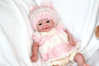 Thumbnail for A baby doll dressed in a pink and white outfit, featuring a cute design and soft fabric.