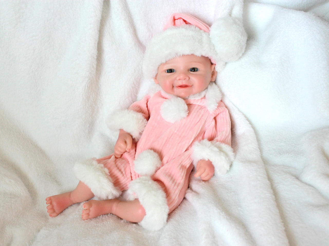 A baby doll wearing a pink and white outfit, featuring a sweet expression and soft, cuddly features.