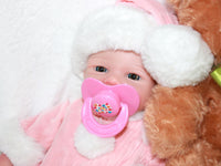 Thumbnail for A baby doll with a pacifier rests on a soft blanket, showcasing its cute features and gentle expression.