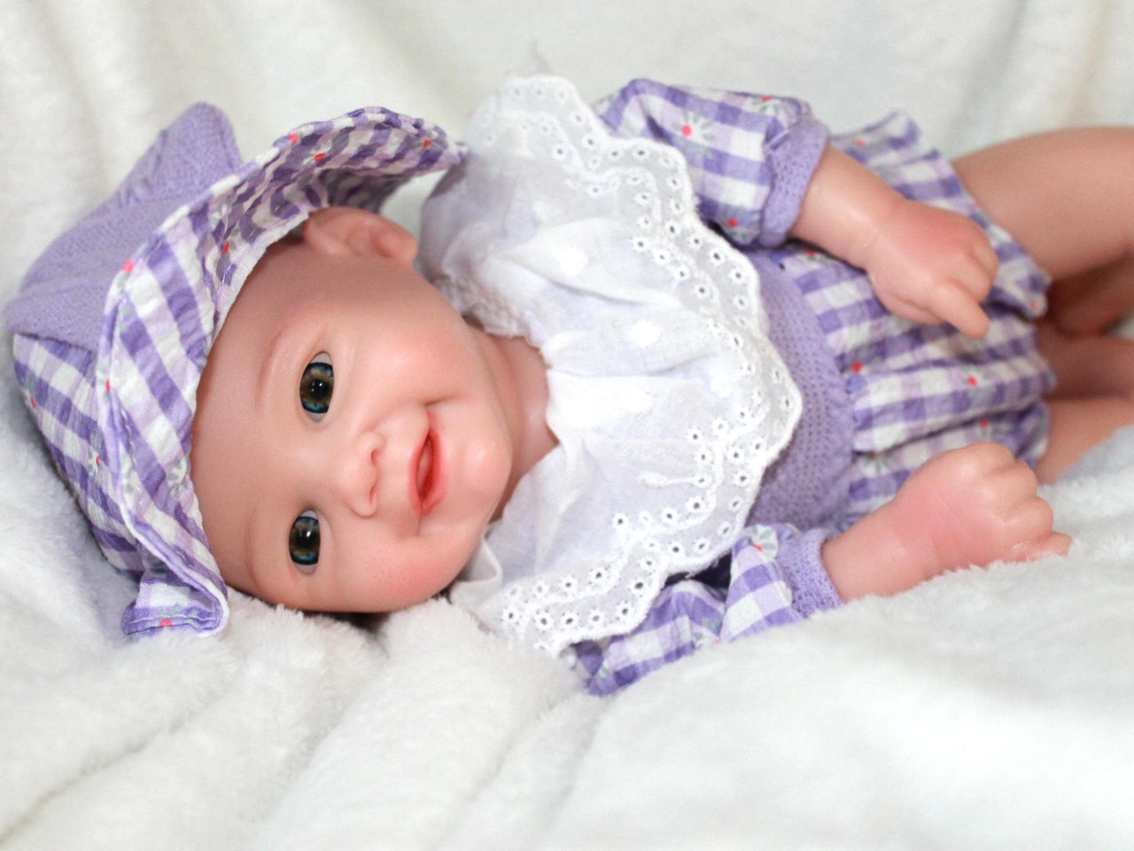 A baby doll dressed in a purple and white dress, featuring a sweet expression and soft, lifelike features.