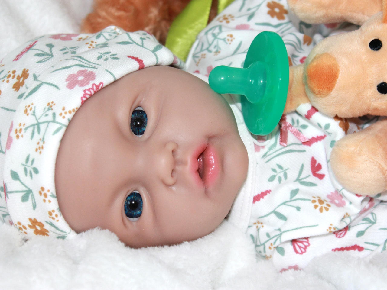 A baby doll lying on a bed next to a plush stuffed animal, evoking a sense of comfort and childhood innocence.
