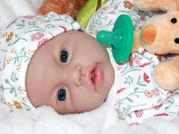 Thumbnail for A baby doll lying on a bed next to a plush stuffed animal, evoking a sense of comfort and childhood innocence.