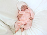 Thumbnail for A baby doll positioned on a patterned blanket, emphasizing its cute appearance and soft texture.