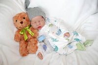 Thumbnail for A baby doll positioned on a blanket, featuring a pacifier next to it.