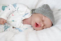 Thumbnail for A baby doll positioned on a blanket, featuring a pacifier next to it.