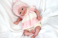 Thumbnail for A cute baby doll wearing pink attire and a hat, positioned on a light background.