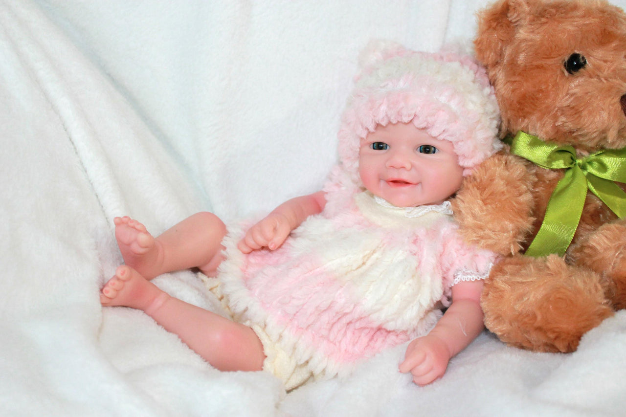 A plush teddy bear is positioned next to a baby doll, showcasing a charming display of childhood toys.