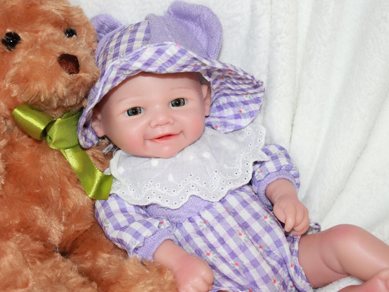 A baby doll dressed in a purple and white dress, featuring a sweet expression and soft, lifelike features.