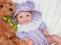 Thumbnail for A baby doll dressed in a purple and white dress, featuring a sweet expression and soft, lifelike features.