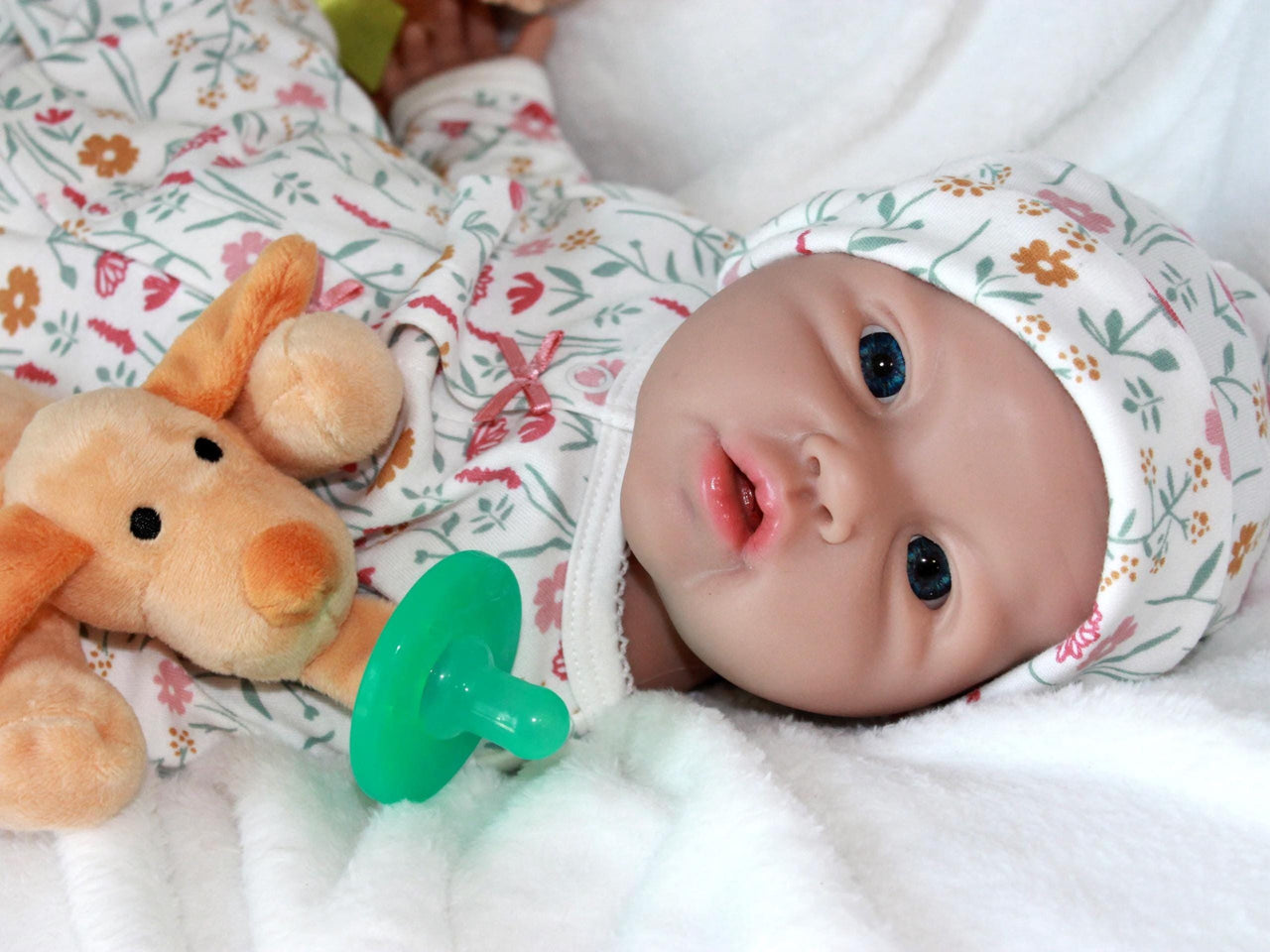 A baby doll resting on a bed beside a soft stuffed animal, creating a cozy and playful scene.