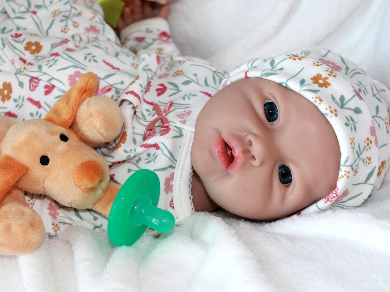 A baby doll resting on a bed beside a soft stuffed animal, creating a cozy and playful scene.