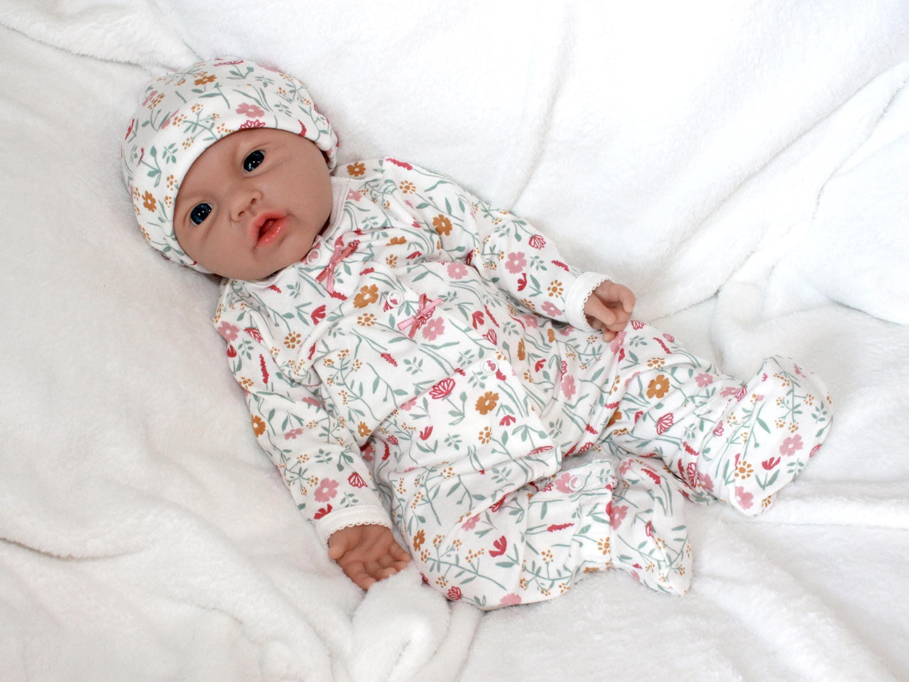 A baby doll resting on a bed beside a soft stuffed animal, creating a cozy and playful scene.