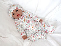 Thumbnail for A baby doll resting on a bed beside a soft stuffed animal, creating a cozy and playful scene.