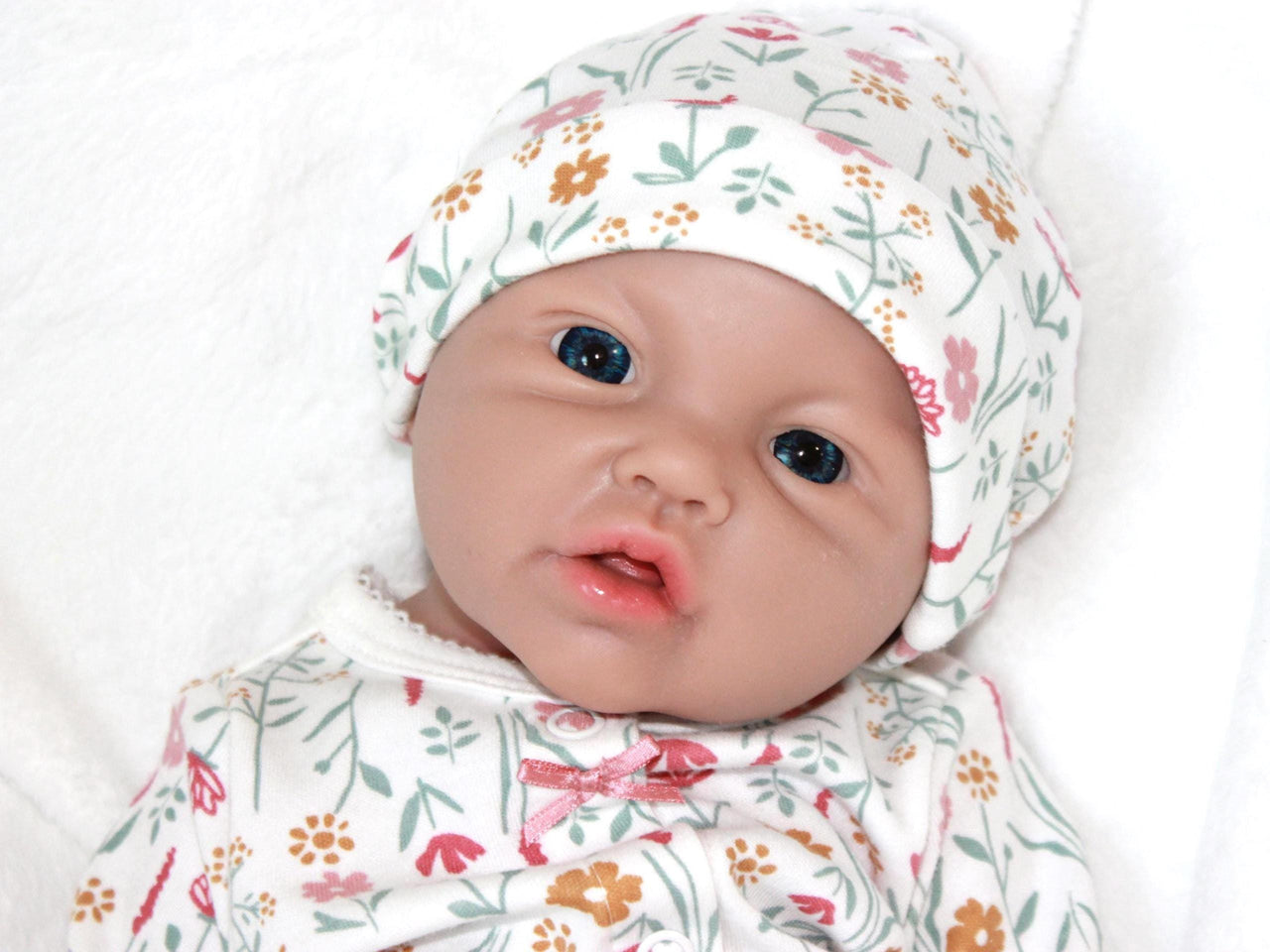 A baby doll resting on a bed beside a soft stuffed animal, creating a cozy and playful scene.