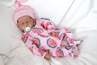 Thumbnail for A baby doll holding a pacifier, dressed in a colorful outfit, with a gentle expression on its face.