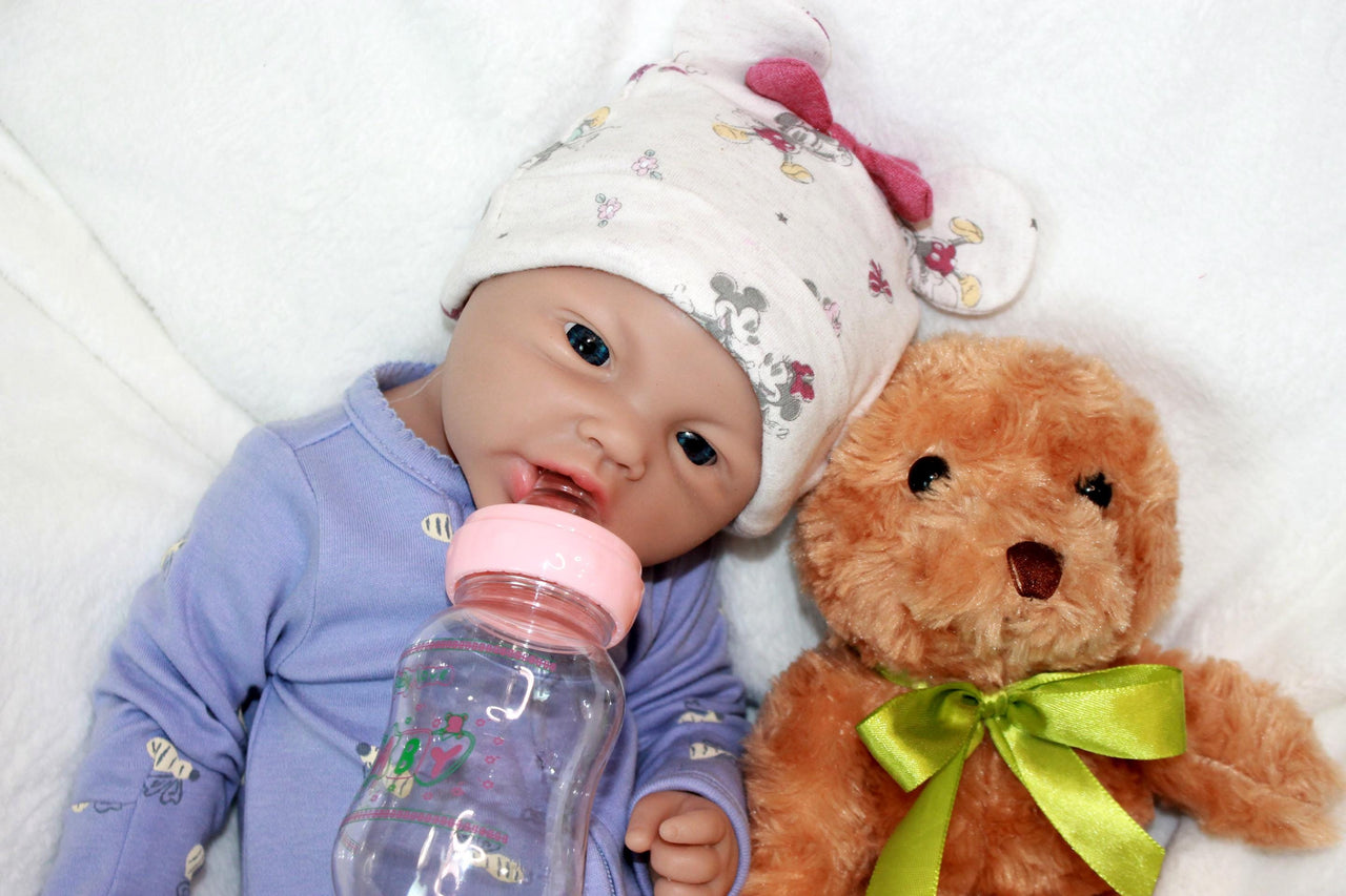 A baby doll is positioned on a blanket with a teddy bear, symbolizing innocence and the joy of playtime.