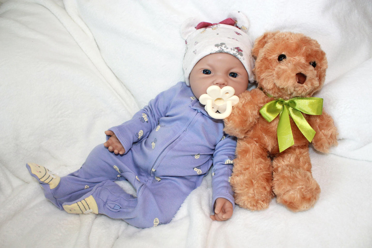 A baby doll lies on a colorful blanket next to a teddy bear, evoking a sense of warmth and childhood comfort.