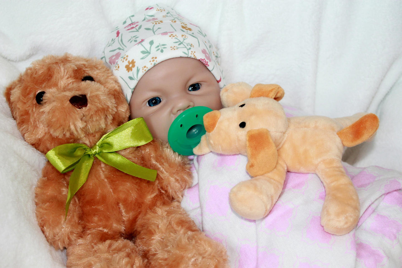 A baby doll lies on a colorful blanket next to a teddy bear, evoking a sense of warmth and childhood comfort.