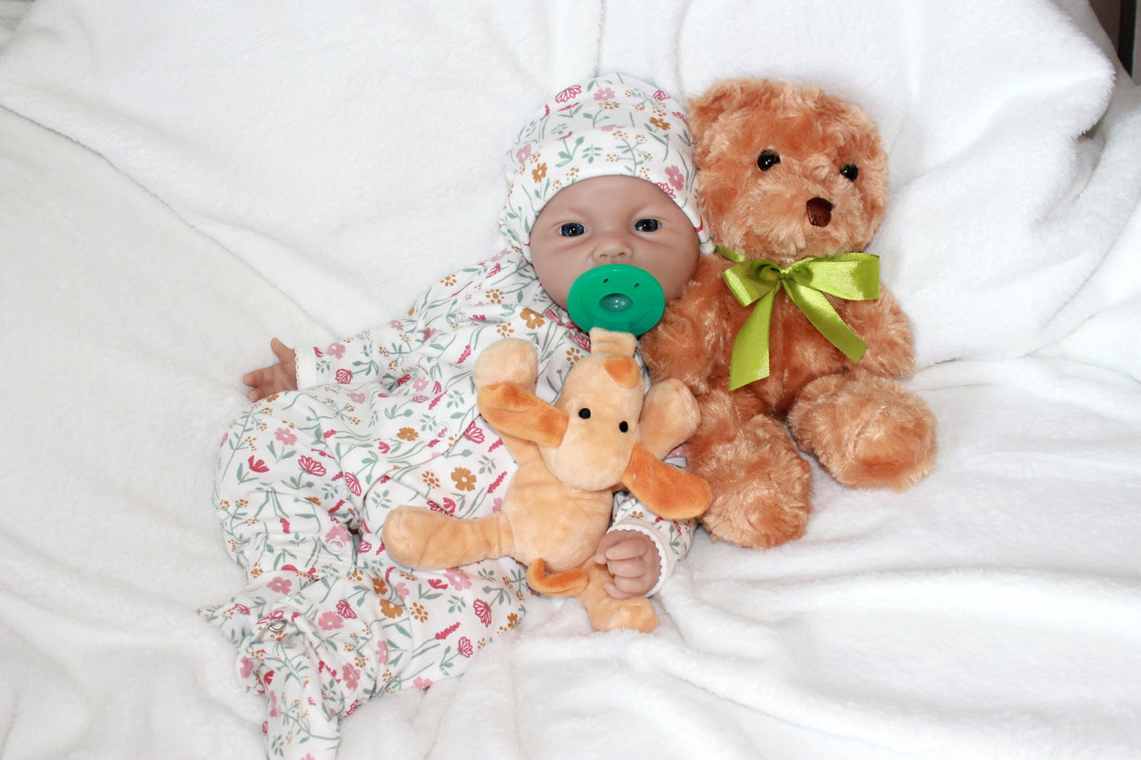 A baby doll lies on a colorful blanket next to a teddy bear, evoking a sense of warmth and childhood comfort.