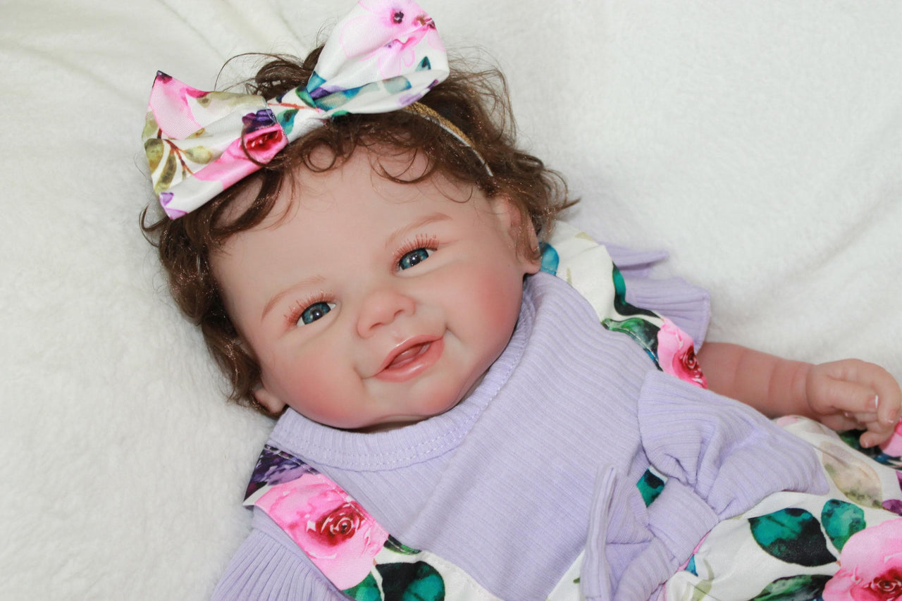 A baby doll wearing a purple dress and a decorative flower headband.