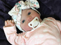 Thumbnail for A baby doll resting on a bed beside, creating a cozy and playful scene.