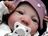 Thumbnail for A baby dressed in floral rests on a cozy blanket, with a peaceful expression