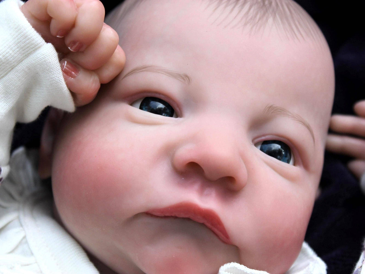 A close up of a reborn baby with its eyes open.