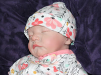 Thumbnail for A baby in pink floral pajamas peacefully lying down on a soft surface.