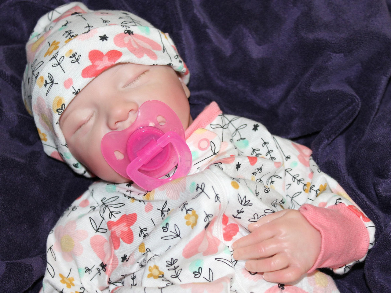 A baby dressed in flowered pajamas, comfortably lying down with a serene expression.