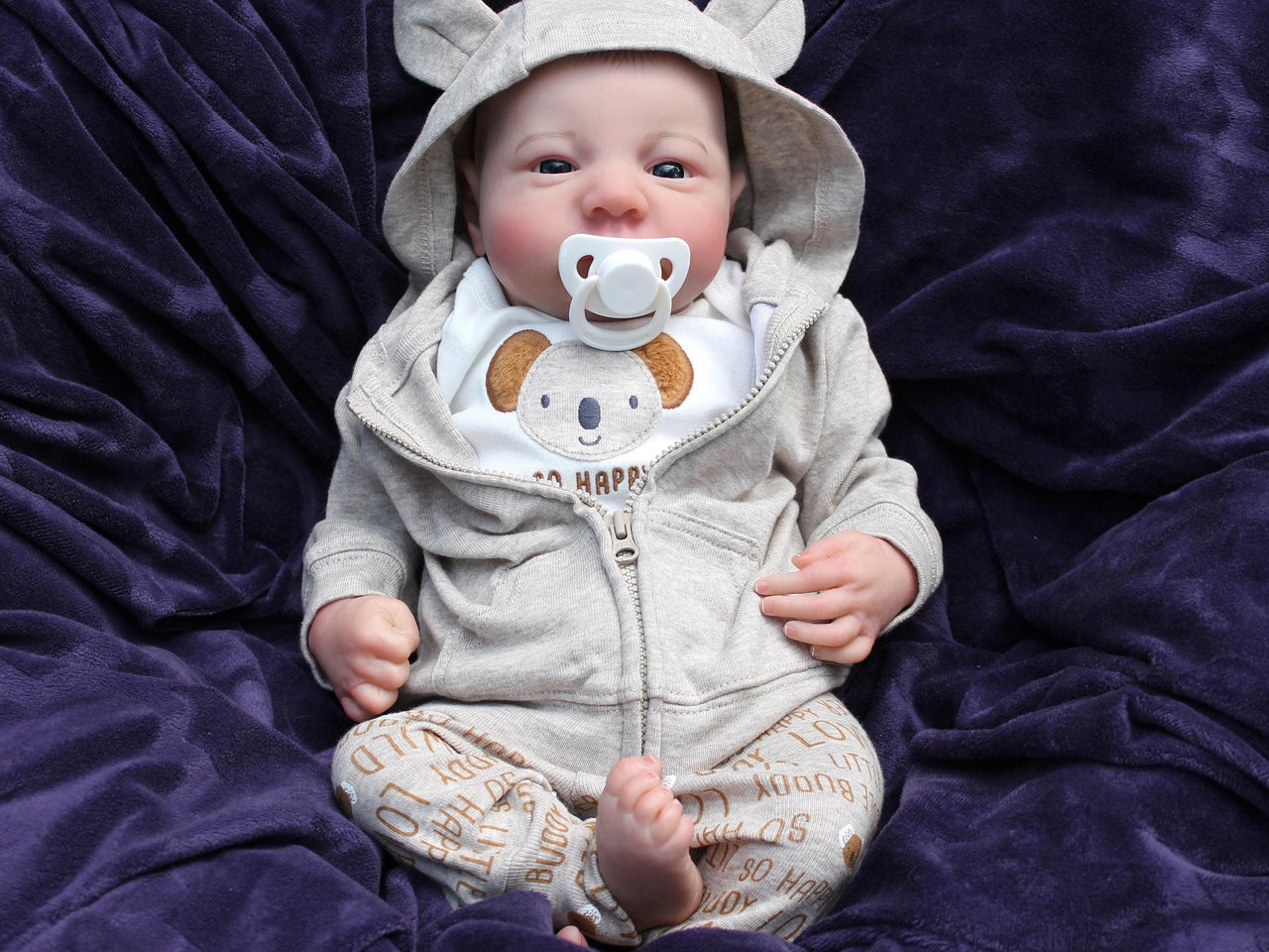 An infant wearing a hat, comfortably resting on a colorful blanket, exuding a sense of tranquilit