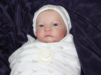 Thumbnail for An infant wearing a hat, comfortably resting on a colorful blanket, exuding a sense of tranquilit